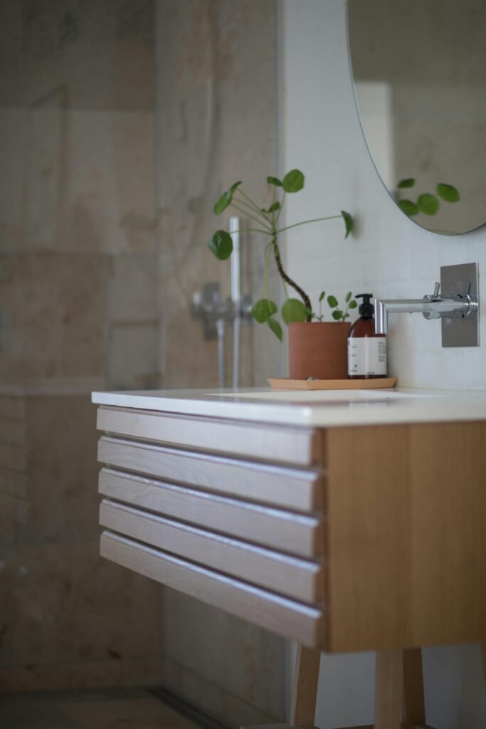 pexels-photo-1358901-1358901 Contemporary bathroom featuring a sleek sink, wooden vanity, and green potted plant decor.